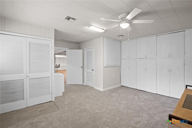 unfurnished bedroom with multiple closets, ceiling fan, and light carpet