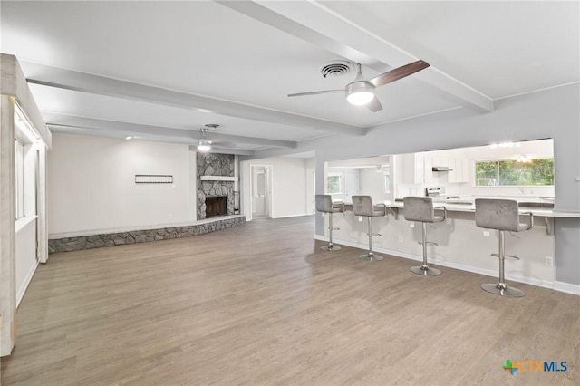 interior space with ceiling fan, beam ceiling, light hardwood / wood-style flooring, and a fireplace