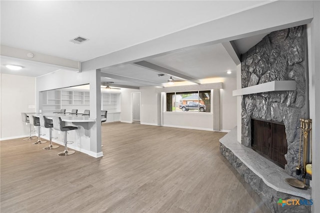 living room with beam ceiling, ceiling fan, hardwood / wood-style floors, and a fireplace