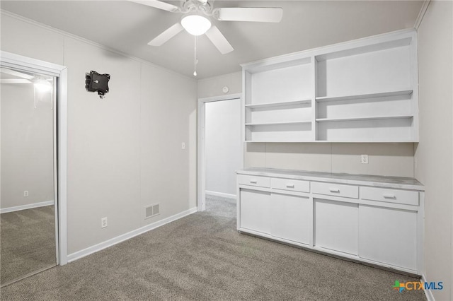 interior space featuring light carpet, ornamental molding, and ceiling fan