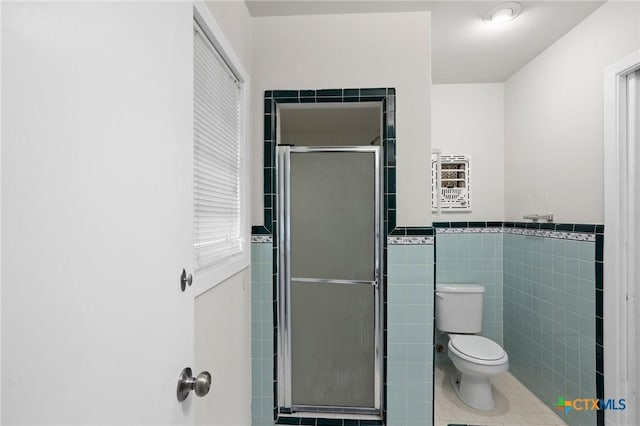 bathroom with heating unit, tile walls, tile patterned flooring, an enclosed shower, and toilet