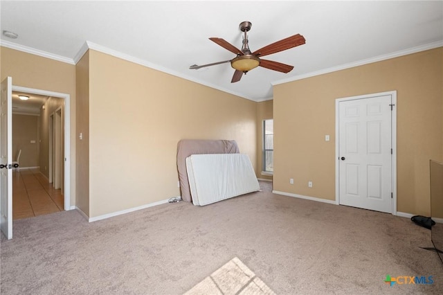 unfurnished bedroom featuring crown molding, carpet flooring, a ceiling fan, and baseboards