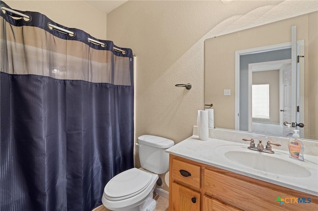 bathroom featuring a shower with shower curtain, toilet, vanity, and a textured wall