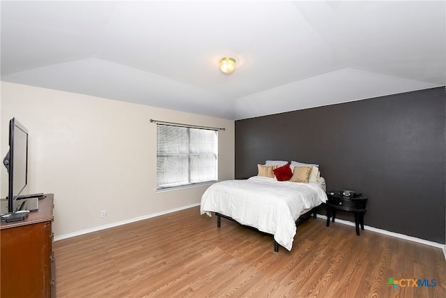 bedroom with wood-type flooring and vaulted ceiling