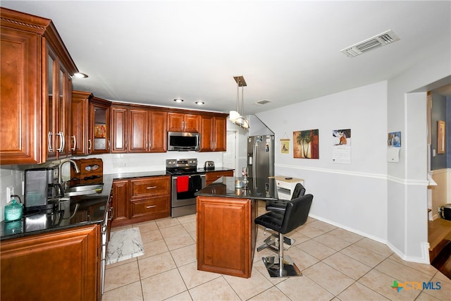 kitchen featuring sink, stainless steel appliances, light tile patterned floors, a breakfast bar area, and a kitchen island