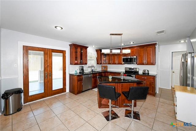 kitchen featuring french doors, stainless steel appliances, light tile patterned floors, decorative light fixtures, and a kitchen island