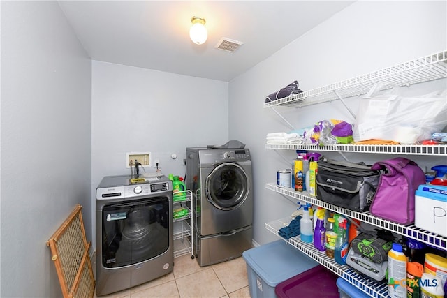 clothes washing area featuring separate washer and dryer and light tile patterned floors