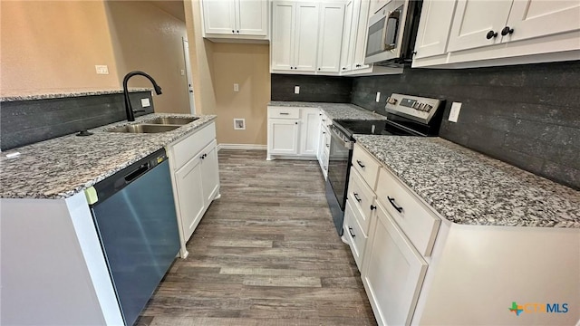 kitchen featuring tasteful backsplash, a sink, white cabinets, appliances with stainless steel finishes, and wood finished floors