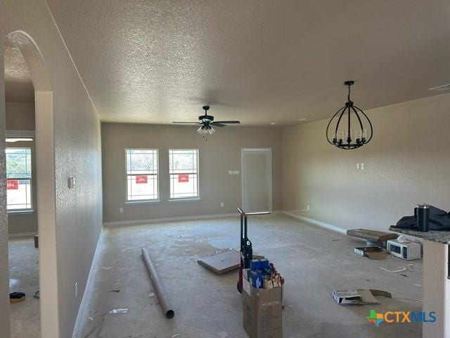 unfurnished living room featuring ceiling fan, a wealth of natural light, and a textured ceiling