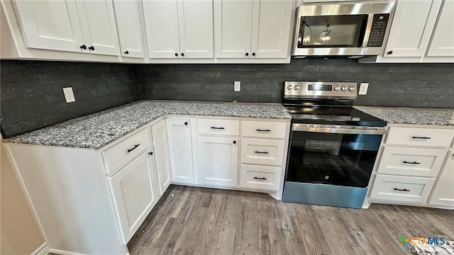 kitchen with white cabinets, wood finished floors, and stainless steel appliances