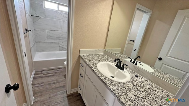 bathroom featuring a textured wall, wood finished floors, toilet, and vanity