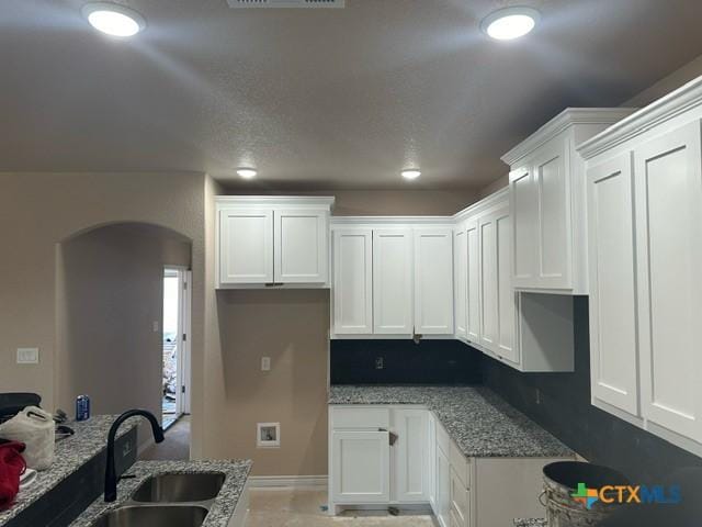 kitchen with sink, white cabinets, and light stone counters