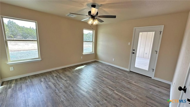 empty room with wood finished floors, baseboards, ceiling fan, and visible vents