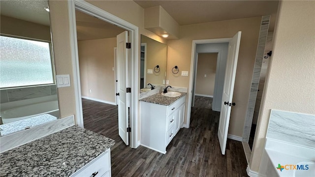 bathroom featuring vanity, baseboards, a garden tub, and wood finished floors