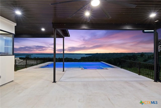 pool at dusk featuring a fenced in pool, a patio, and a water view