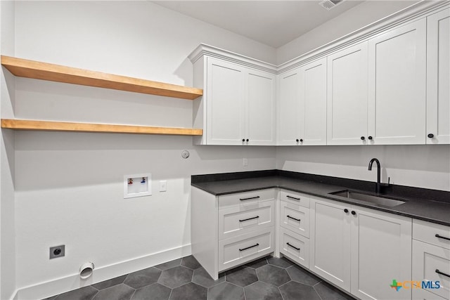laundry area featuring a sink, hookup for a washing machine, cabinet space, electric dryer hookup, and dark tile patterned flooring
