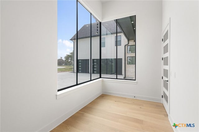 spare room with plenty of natural light, wood finished floors, and baseboards