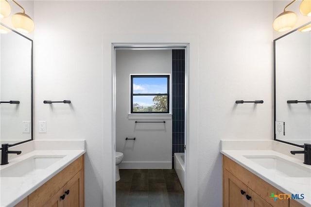 bathroom with two vanities, a bath, toilet, and a sink