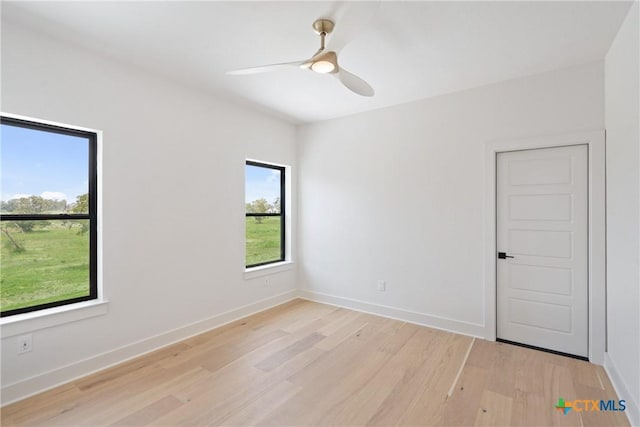 spare room with baseboards, a ceiling fan, and light wood finished floors