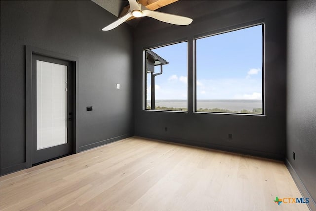 empty room with lofted ceiling, light wood-style floors, and ceiling fan