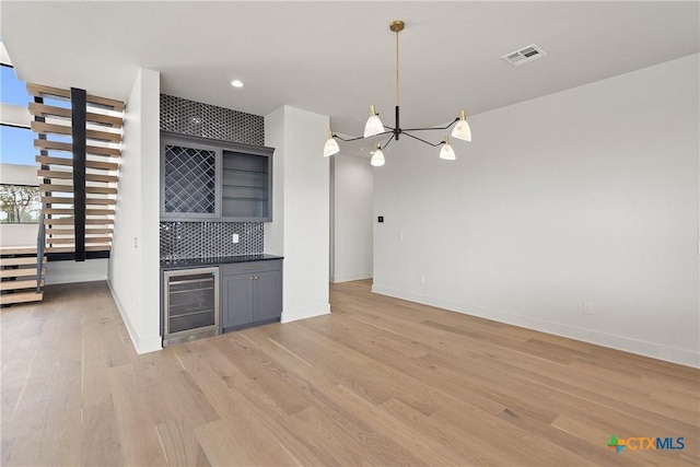 kitchen with dark countertops, a chandelier, gray cabinets, wine cooler, and visible vents