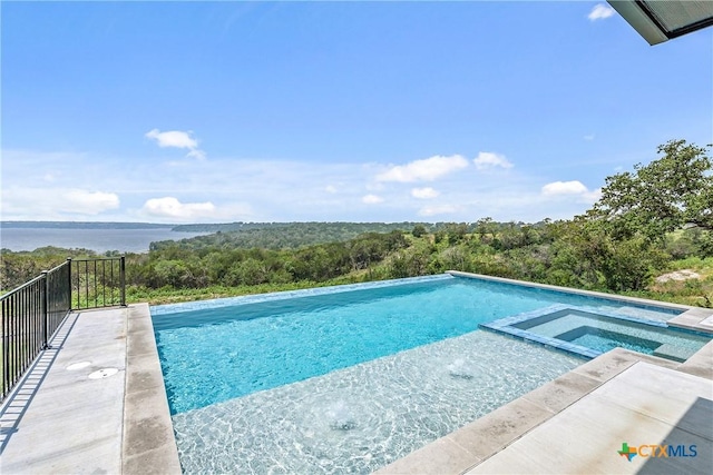 view of swimming pool with a forest view, a water view, and a pool with connected hot tub