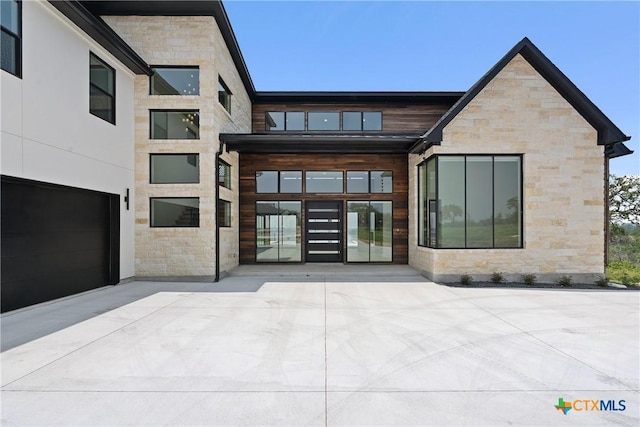 rear view of property with a garage and stone siding