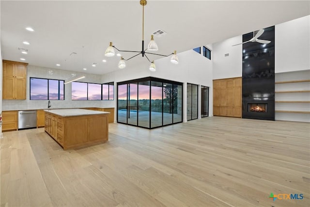 kitchen featuring light wood finished floors, light countertops, stainless steel dishwasher, a kitchen island, and open floor plan