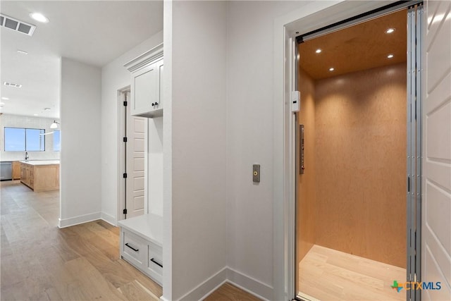mudroom featuring elevator, light wood finished floors, baseboards, visible vents, and recessed lighting