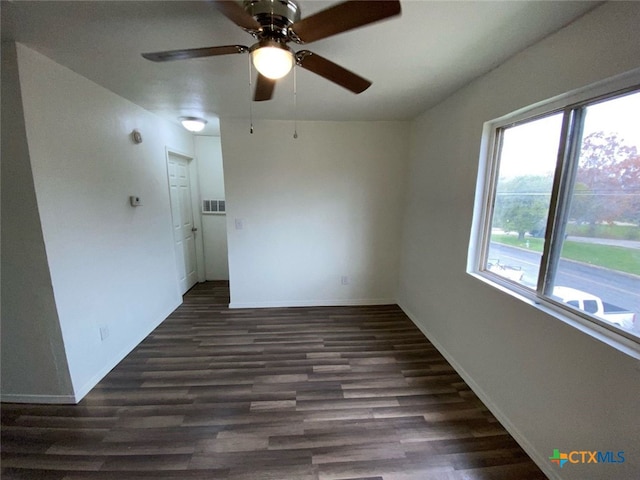 empty room featuring ceiling fan, baseboards, dark wood finished floors, and visible vents