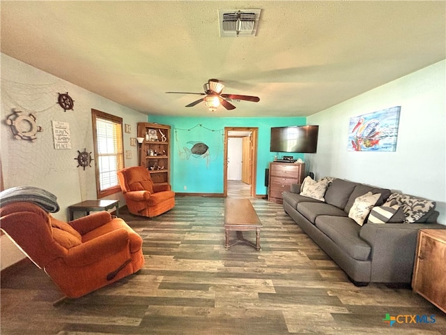 living room with dark wood-type flooring, ceiling fan, and a textured ceiling