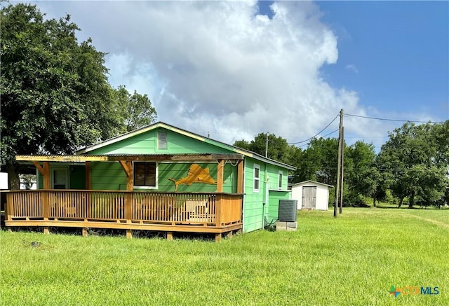 rear view of property with a storage shed, a wooden deck, and a lawn