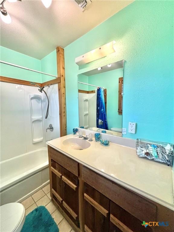 1007 W Monroe Ave, Port Oconnor, TX 77982 - full bath featuring toilet, vanity, shower / bath combination with curtain, tile patterned flooring, and a textured wall