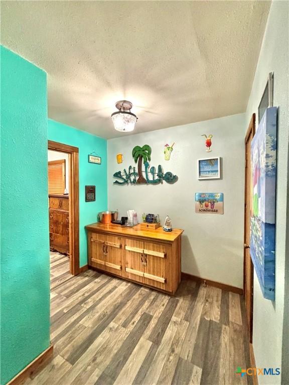 1007 W Monroe Ave, Port Oconnor, TX 77982 - hall with a textured ceiling, wood finished floors, and baseboards