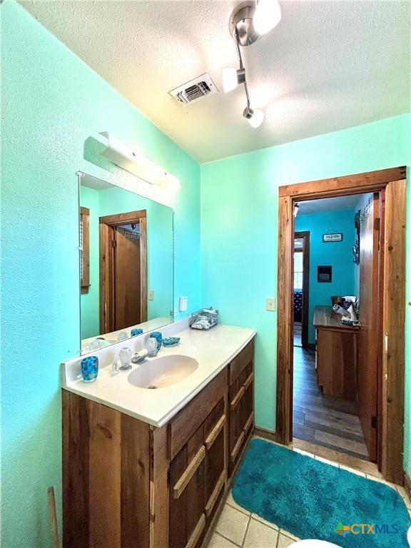 1007 W Monroe Ave, Port Oconnor, TX 77982 - bathroom with a textured ceiling, vanity, a textured wall, and tile patterned flooring