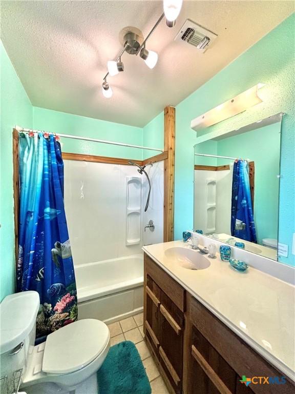 1007 W Monroe Ave, Port Oconnor, TX 77982 - full bath with toilet, vanity, shower / bath combination with curtain, tile patterned floors, and a textured ceiling