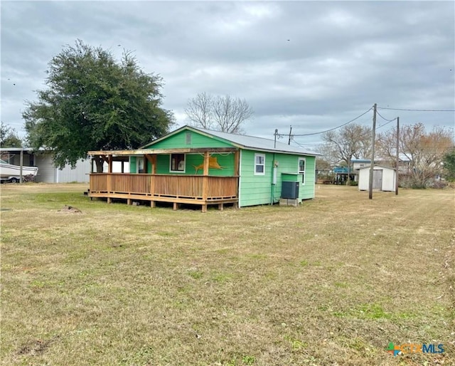 rear view of house with a shed, a wooden deck, a yard, and central AC