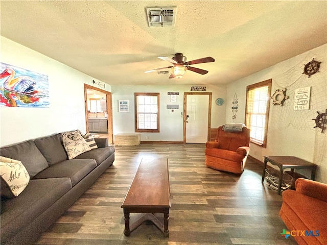 living room featuring ceiling fan, dark hardwood / wood-style flooring, and a textured ceiling