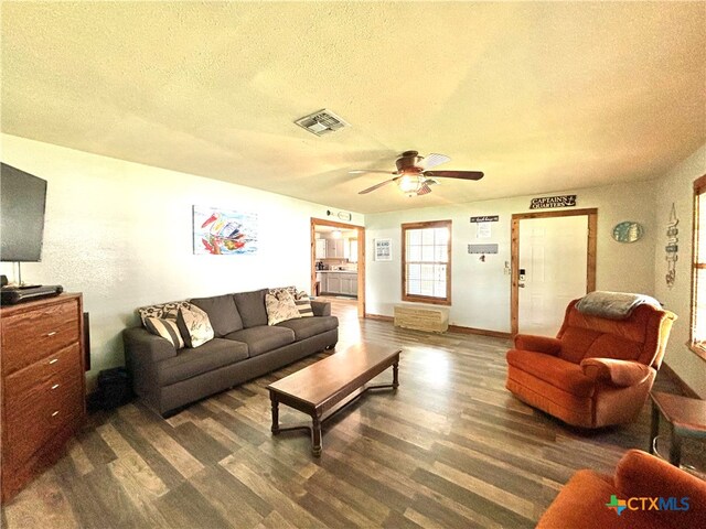 living room with ceiling fan, dark hardwood / wood-style floors, and a textured ceiling