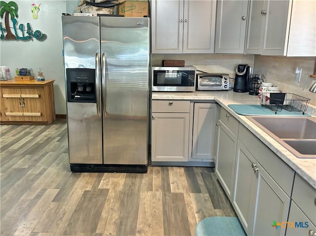 kitchen with stainless steel appliances, gray cabinets, sink, and light hardwood / wood-style flooring