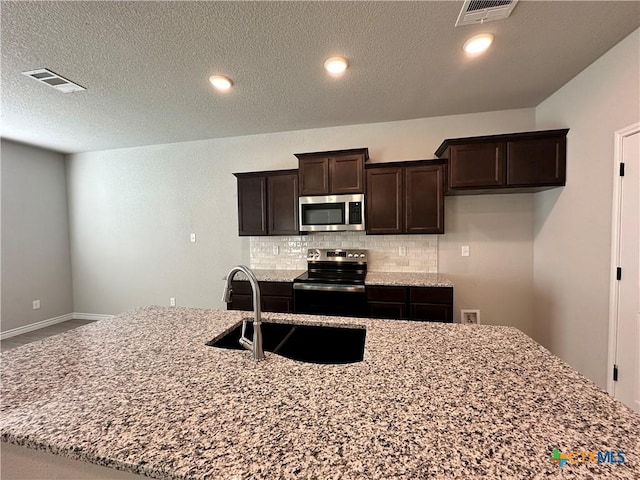 kitchen with dark brown cabinetry, sink, stainless steel appliances, tasteful backsplash, and light stone counters