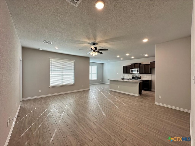 unfurnished living room with ceiling fan, light hardwood / wood-style flooring, and a textured ceiling