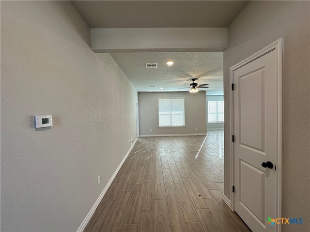 hallway featuring light hardwood / wood-style floors and a textured ceiling