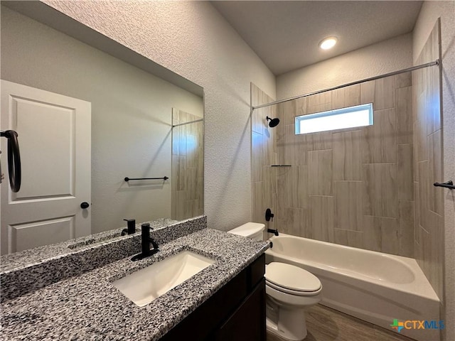 full bathroom featuring vanity, tiled shower / bath combo, and toilet