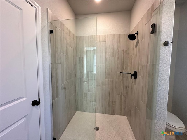 bathroom with toilet and a tile shower