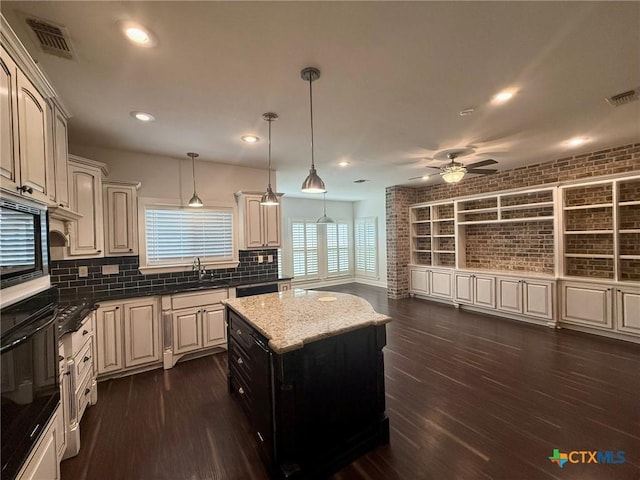 kitchen with decorative backsplash, ceiling fan, sink, decorative light fixtures, and dark stone countertops