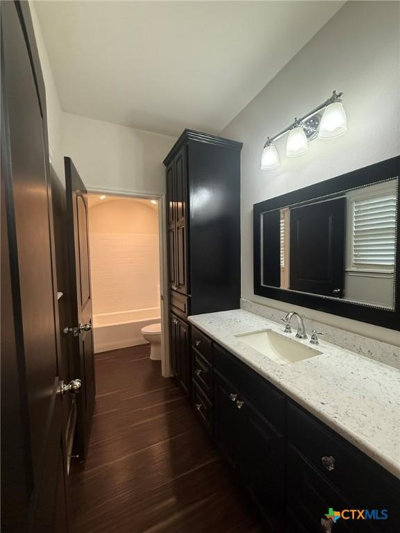 full bathroom featuring shower / washtub combination, toilet, vanity, and hardwood / wood-style flooring