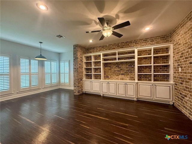 interior space featuring ceiling fan and brick wall