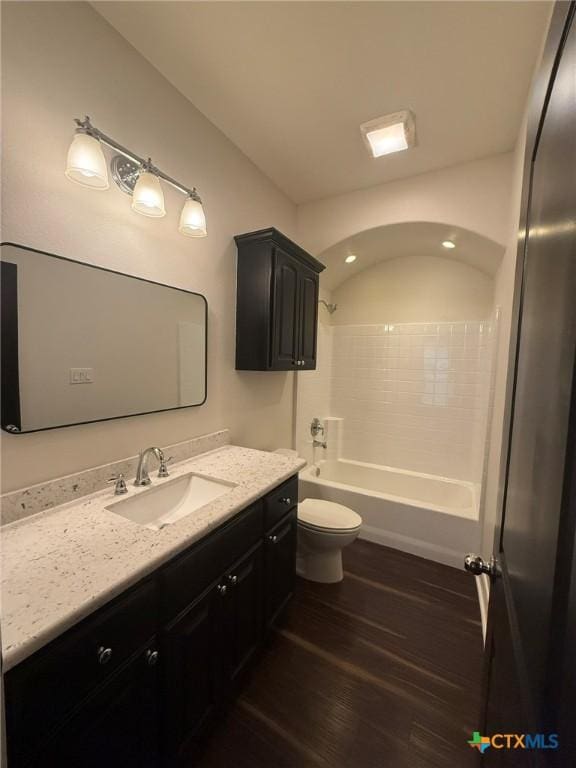 full bathroom featuring hardwood / wood-style flooring, vanity, toilet, and shower / tub combination