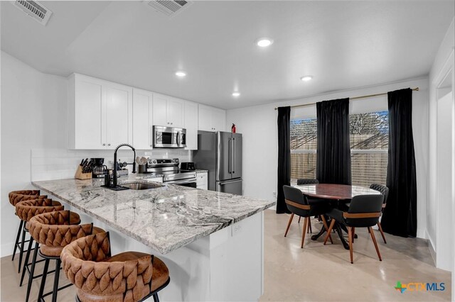 kitchen featuring sink, light stone counters, appliances with stainless steel finishes, a kitchen breakfast bar, and kitchen peninsula